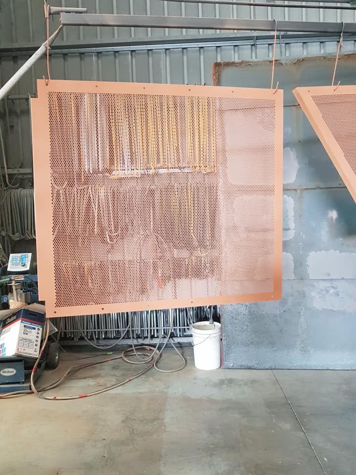 A Large Piece Of Metal Is Hanging From The Ceiling In A Warehouse — Border Security Doors & Powder Coating in Wodonga, VIC