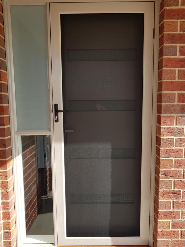 A White Screen Door Is Installed On A Brick Wall — Border Security Doors & Powder Coating in Wodonga, VIC