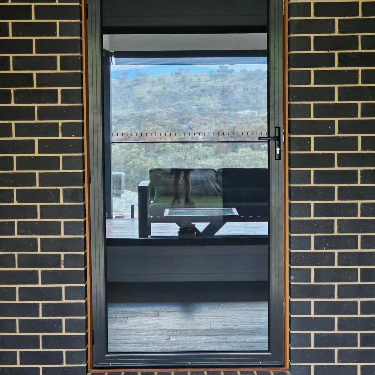 A Brick Wall With A Glass Door — Border Security Doors & Powder Coating in Wodonga, VIC