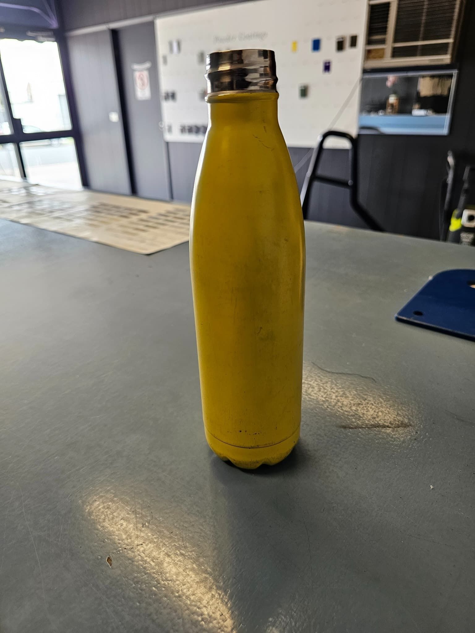 A Yellow Water Bottle Is Sitting On A Table — Border Security Doors & Powder Coating in Wodonga, VIC