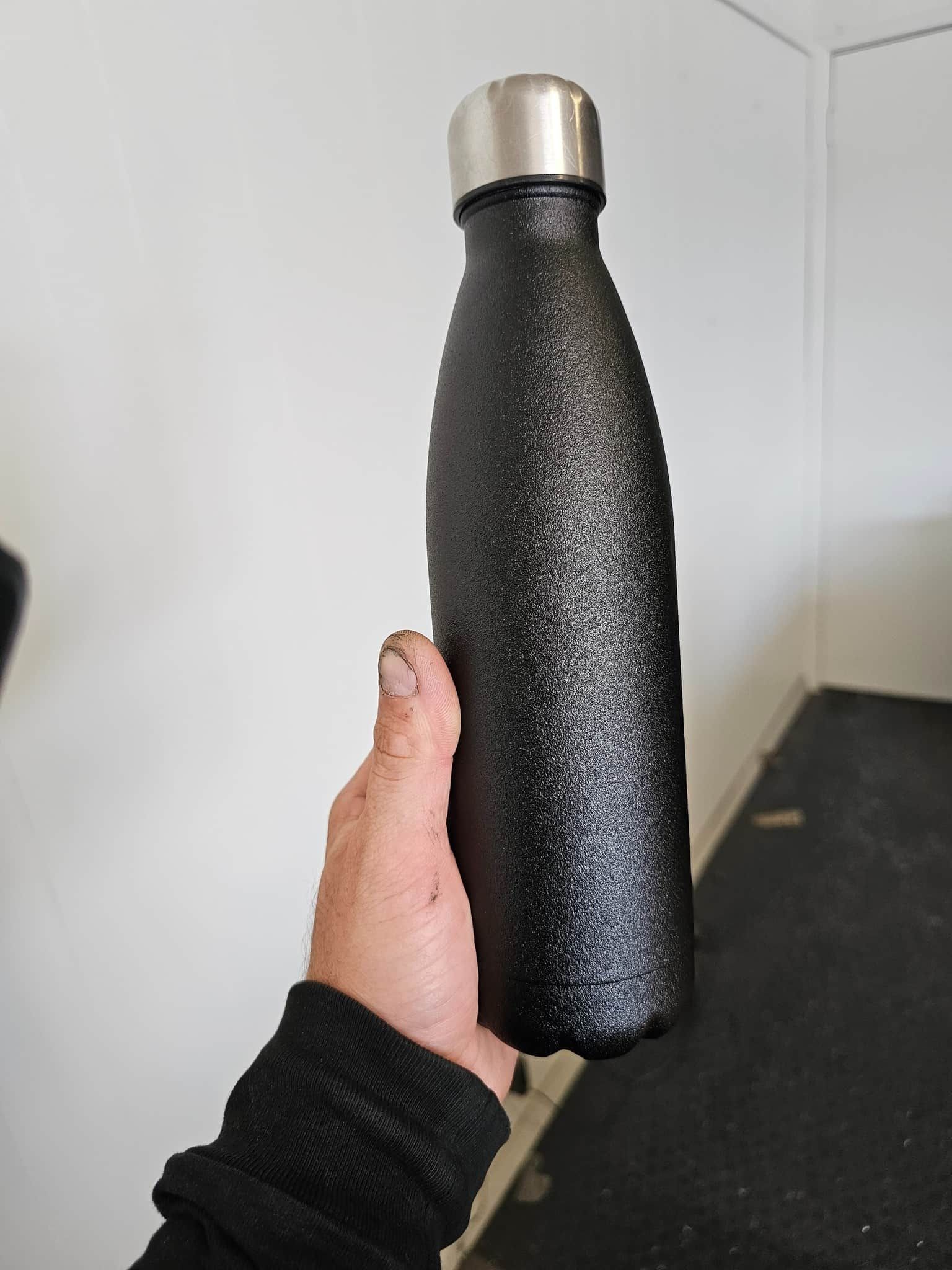 A Person Is Holding A Black Water Bottle — Border Security Doors & Powder Coating in Wodonga, VIC