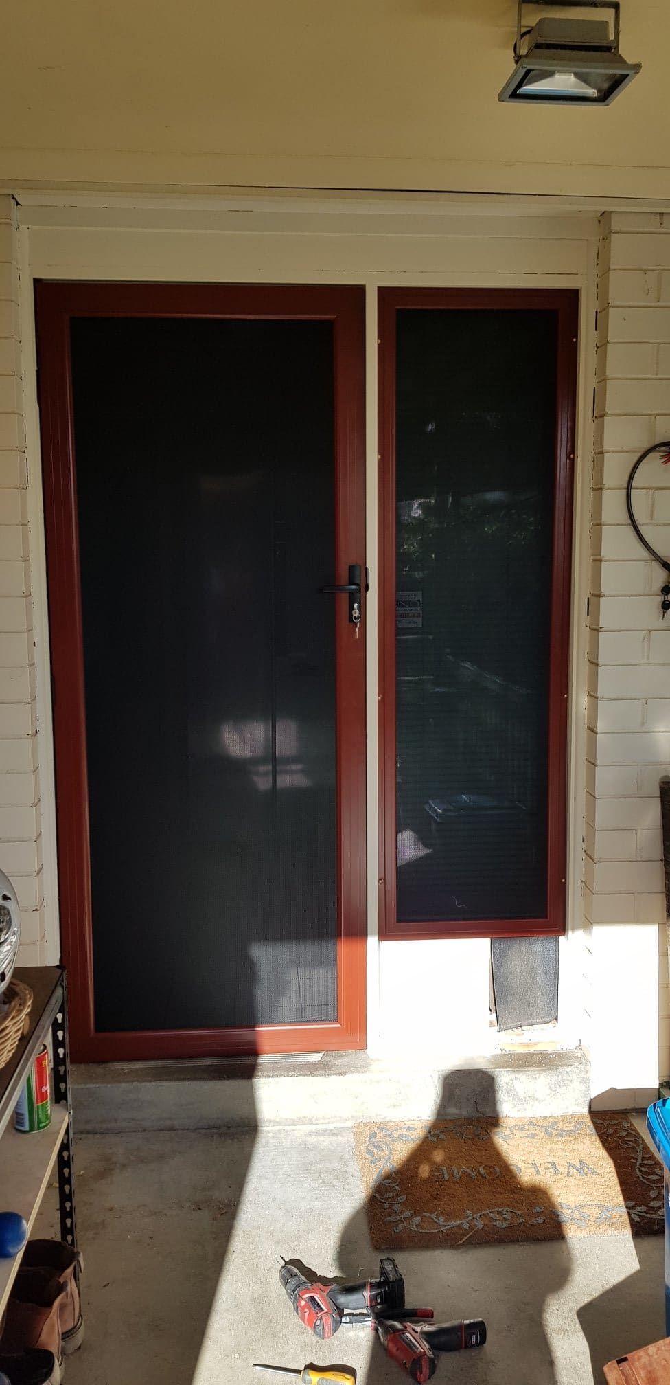 A Screen Door Is Being Installed On A Porch — Border Security Doors & Powder Coating in Wodonga, VIC