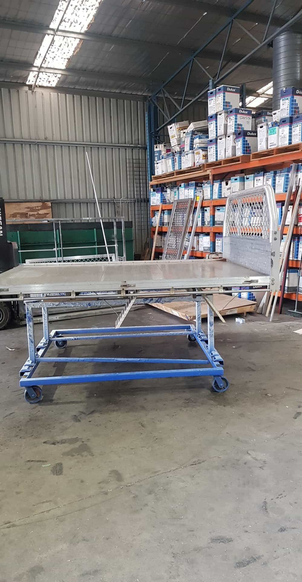 A Table With Wheels Is Sitting In A Warehouse — Border Security Doors & Powder Coating in Wodonga, VIC
