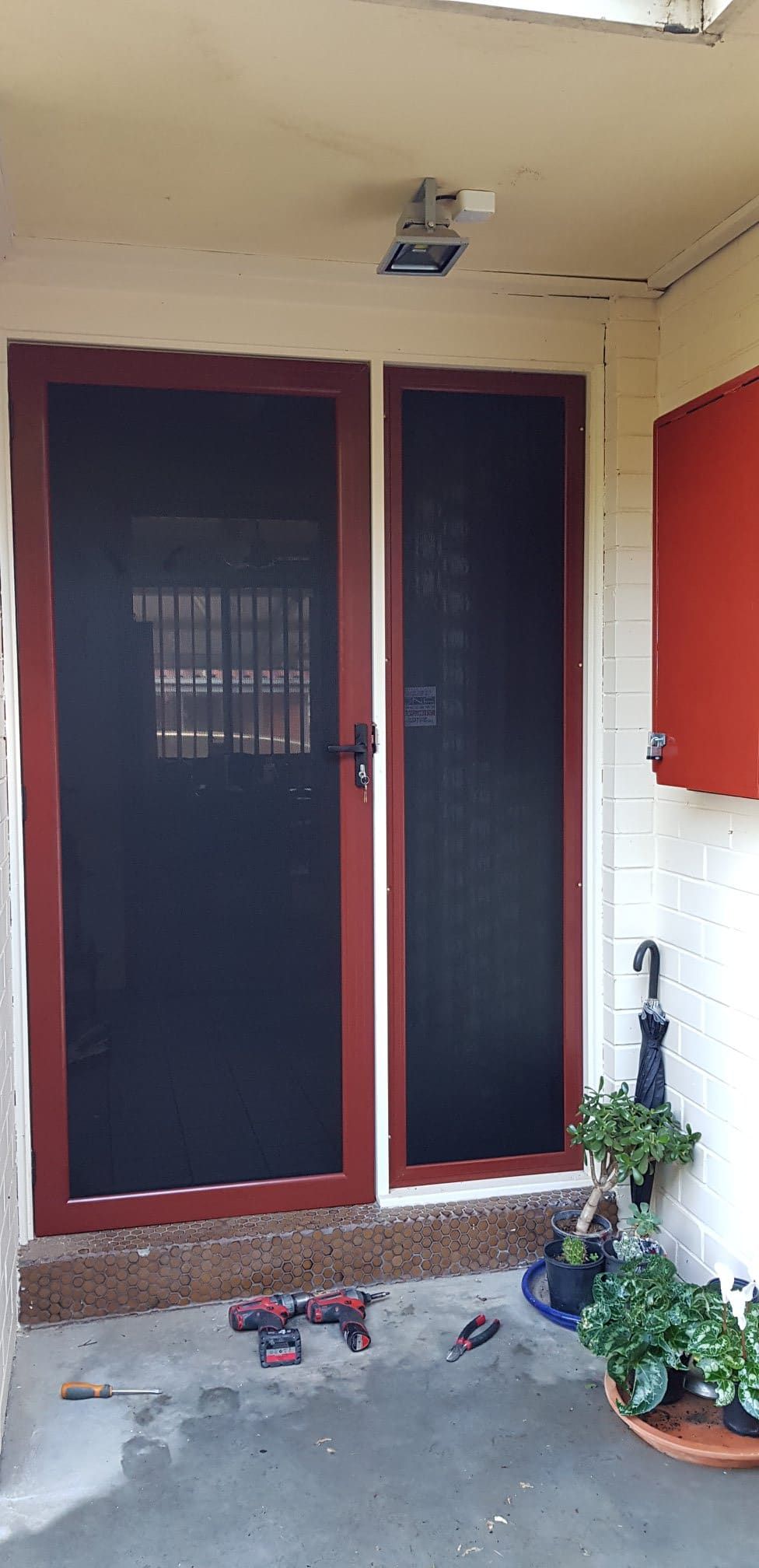 A Door With A Screen Is Sitting Next To A Potted Plant — Border Security Doors & Powder Coating in Wodonga, VIC