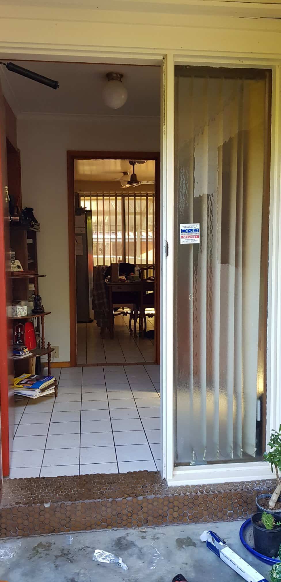 A Sliding Glass Door Is Open To A Living Room — Border Security Doors & Powder Coating in Wodonga, VIC