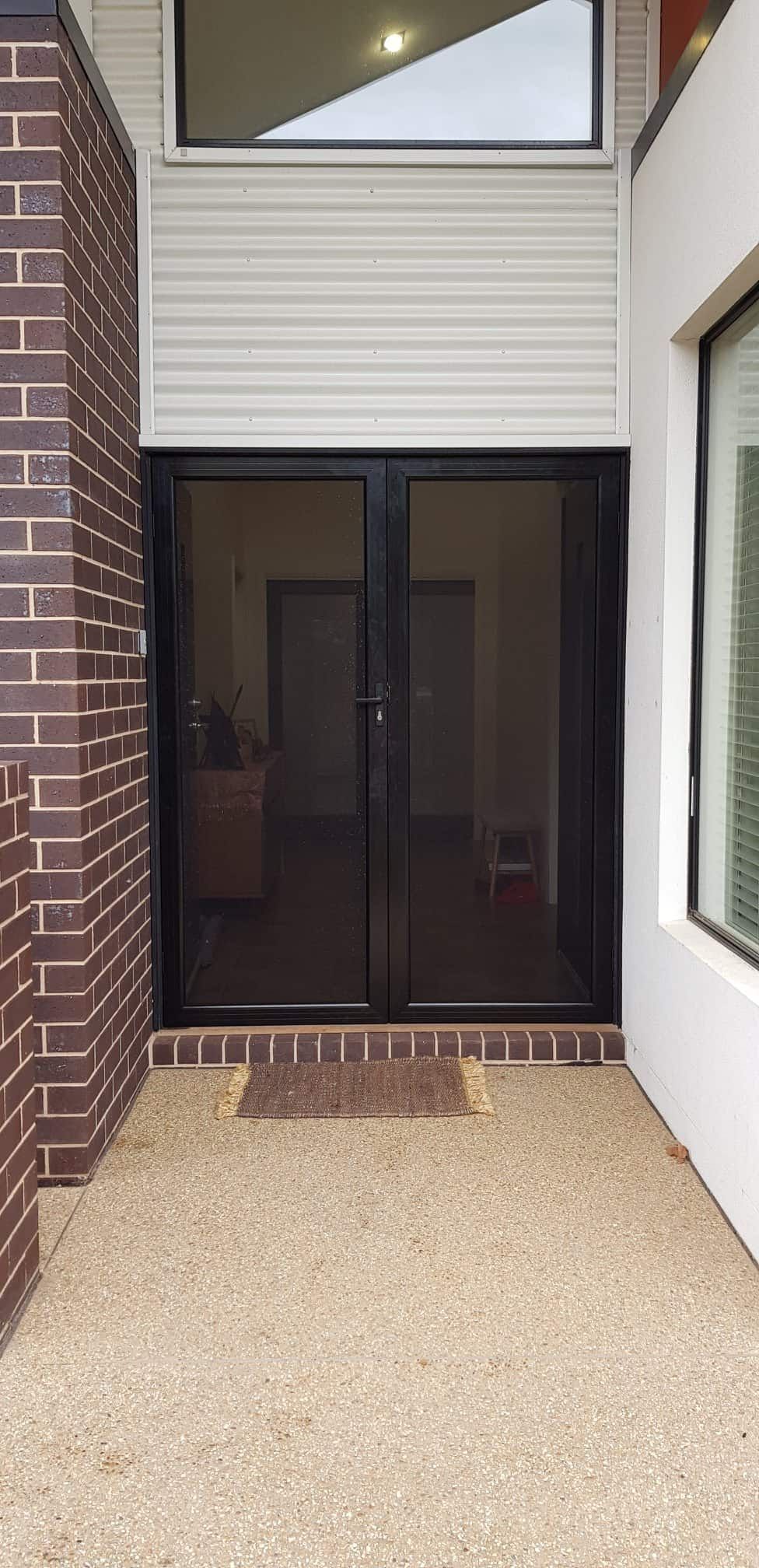 A Patio With Sliding Glass Doors And A Brick Wall — Border Security Doors & Powder Coating in Wangaratta, NSW