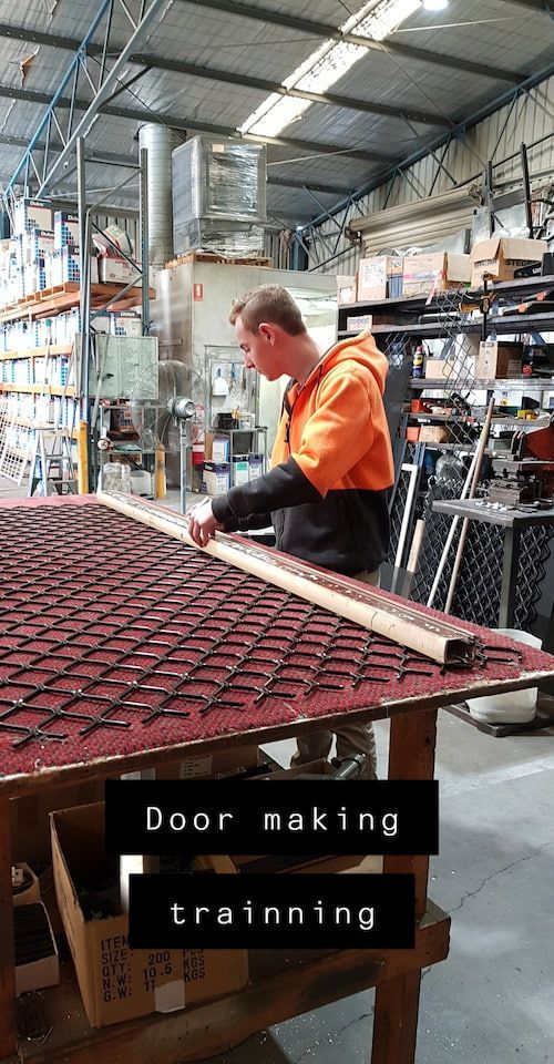 A Man Is Working On A Piece Of Wood In A Warehouse — Border Security Doors & Powder Coating in Wangaratta, NSW