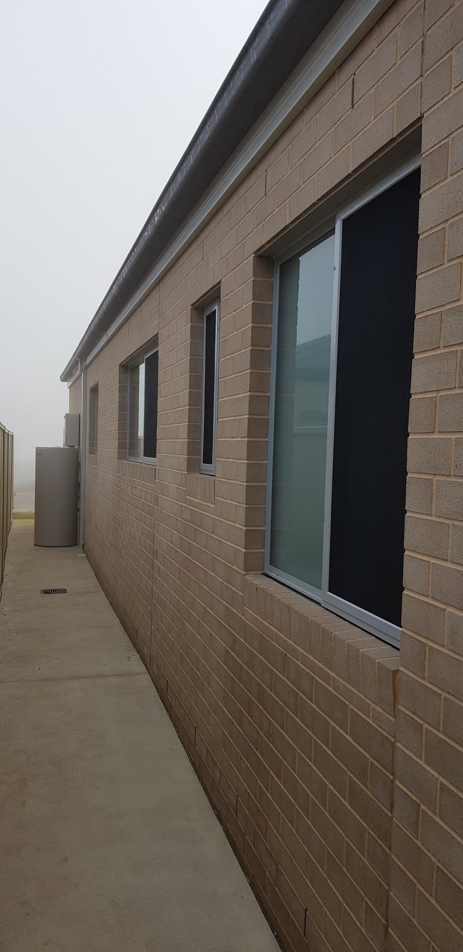 A Brick Building With A Row Of Windows On A Foggy Day — Border Security Doors & Powder Coating in Wodonga, VIC