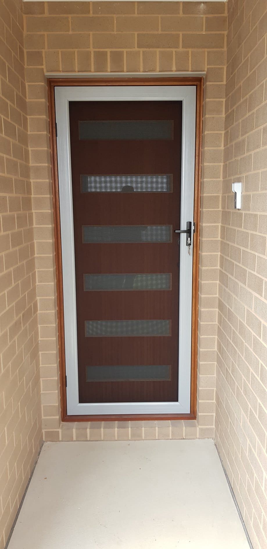 A Door Is Sitting In A Hallway Next To A Brick Wall — Border Security Doors & Powder Coating in Wodonga, VIC