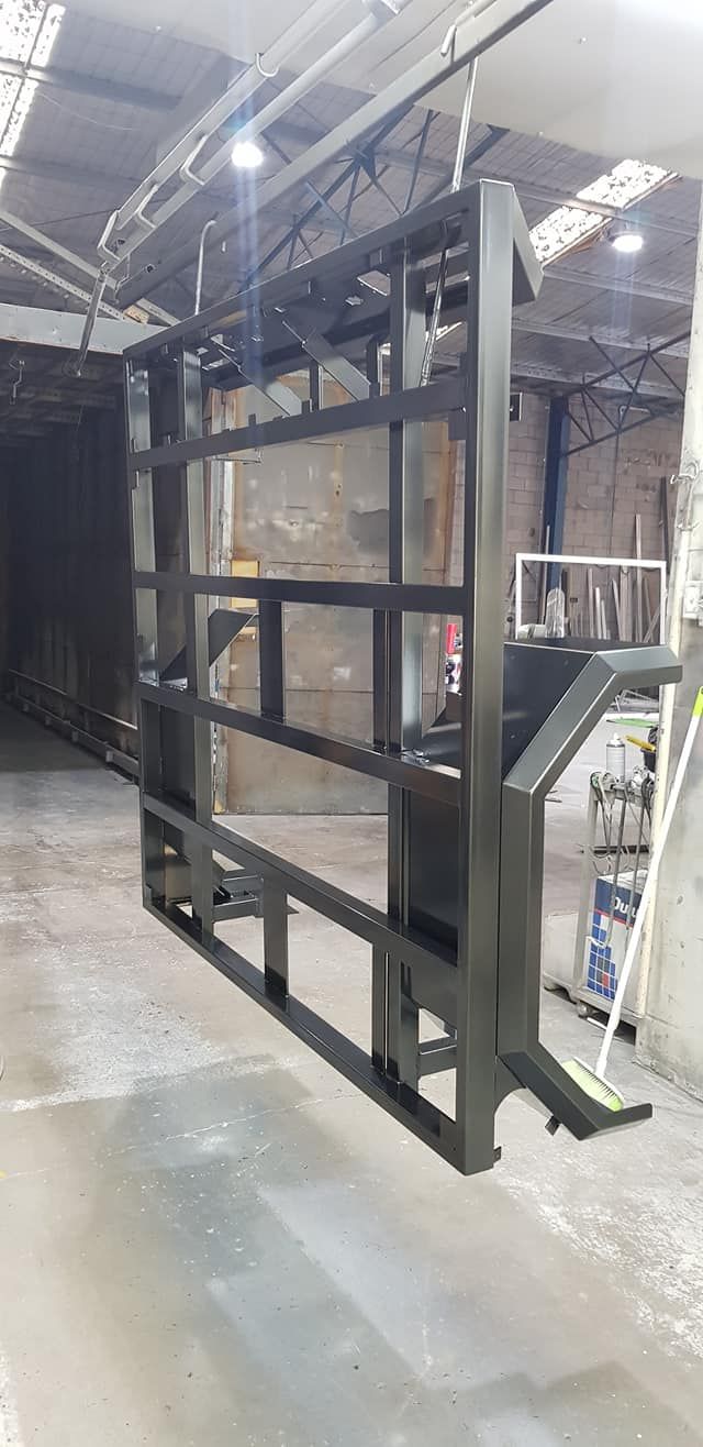 A Large Metal Structure Is Hanging From The Ceiling In A Warehouse — Border Security Doors & Powder Coating in Wodonga, VIC
