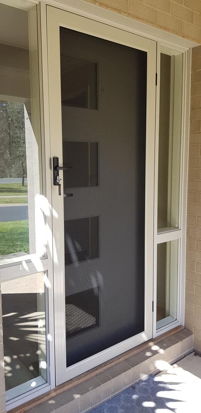 A White Door With A Screen On It Is Sitting Next To A Window — Border Security Doors & Powder Coating in Wodonga, VIC