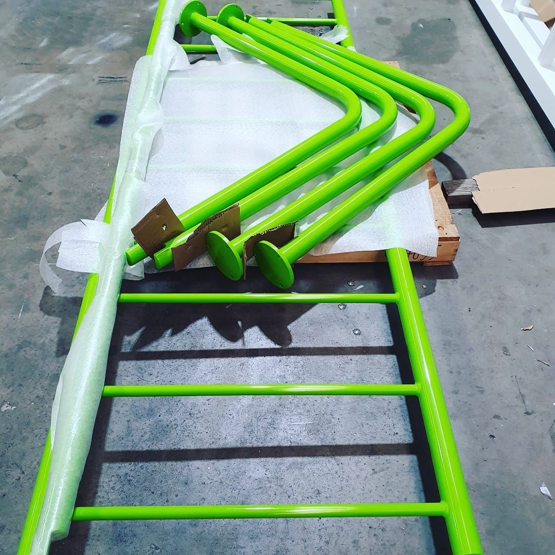 A Bunch Of Green Pipes Are Stacked On Top Of Each Other — Border Security Doors & Powder Coating in Wodonga, VIC