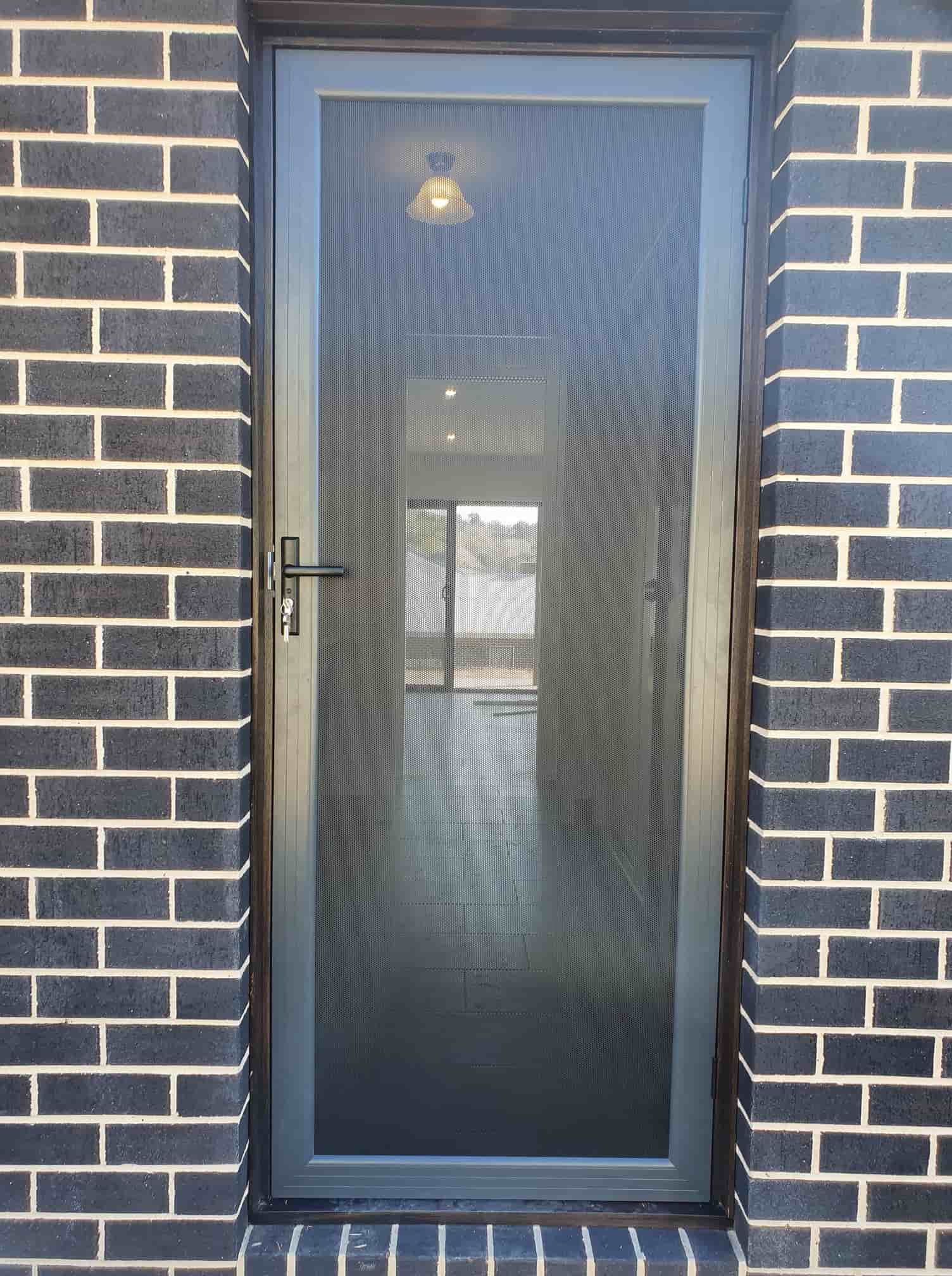 A Door With A Screen On It Is On A Brick Wall — Border Security Doors & Powder Coating in Wodonga, VIC