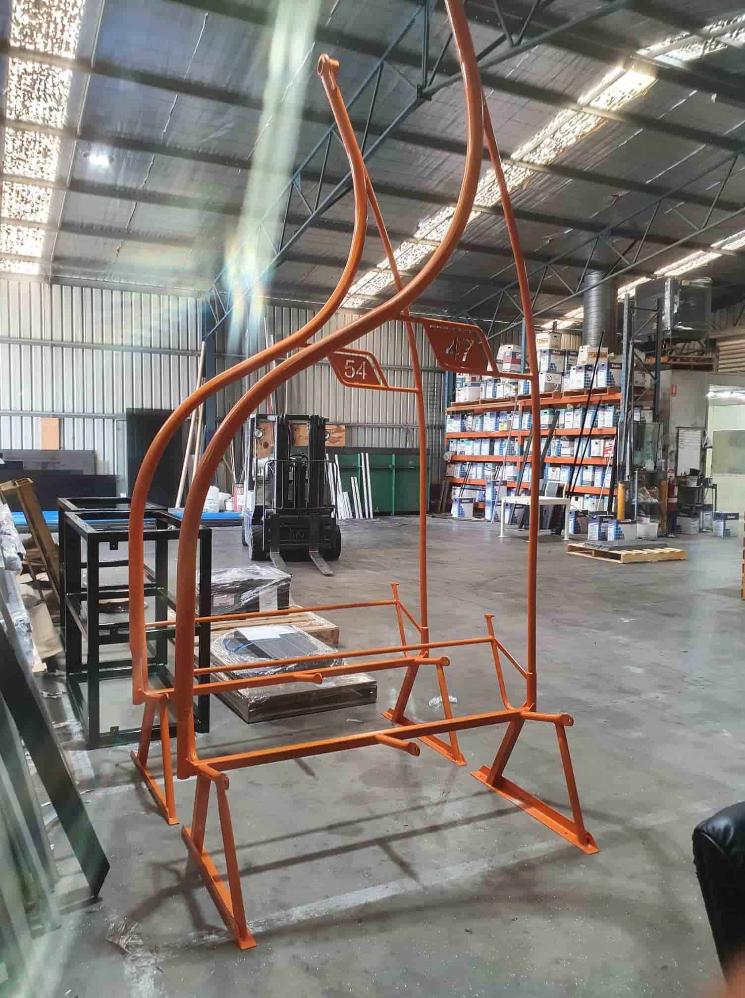 A Large Orange Metal Structure Is Sitting In A Warehouse — Border Security Doors & Powder Coating in Wodonga, VIC