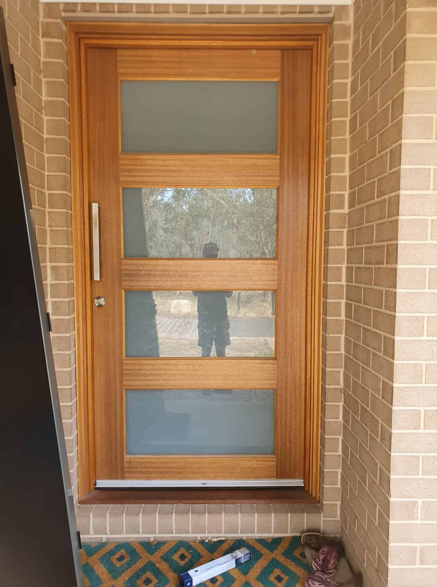 A Wooden Door With Four Windows On A Brick Wall — Border Security Doors & Powder Coating in Wodonga, VIC