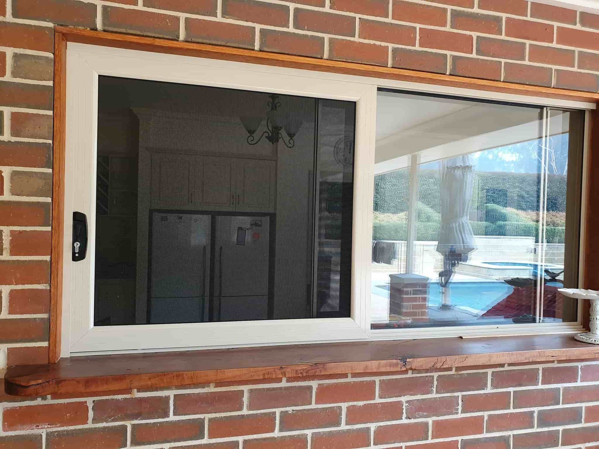 A Large Window In A Brick Wall With A Sliding Glass Door — Border Security Doors & Powder Coating in Wodonga, VIC