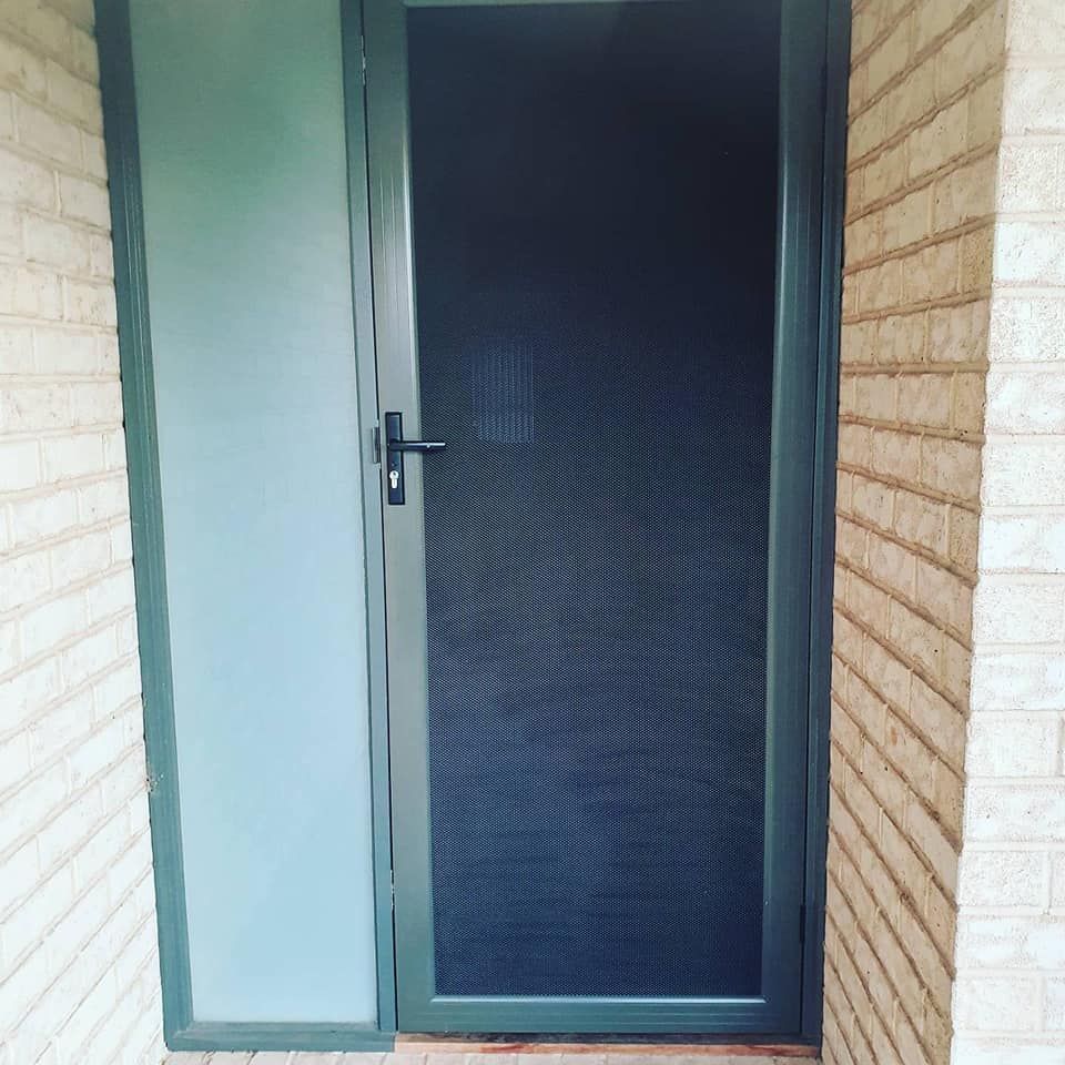 A Screen Door Is Sitting On The Side Of A Brick Wall — Border Security Doors & Powder Coating in Albury, NSW