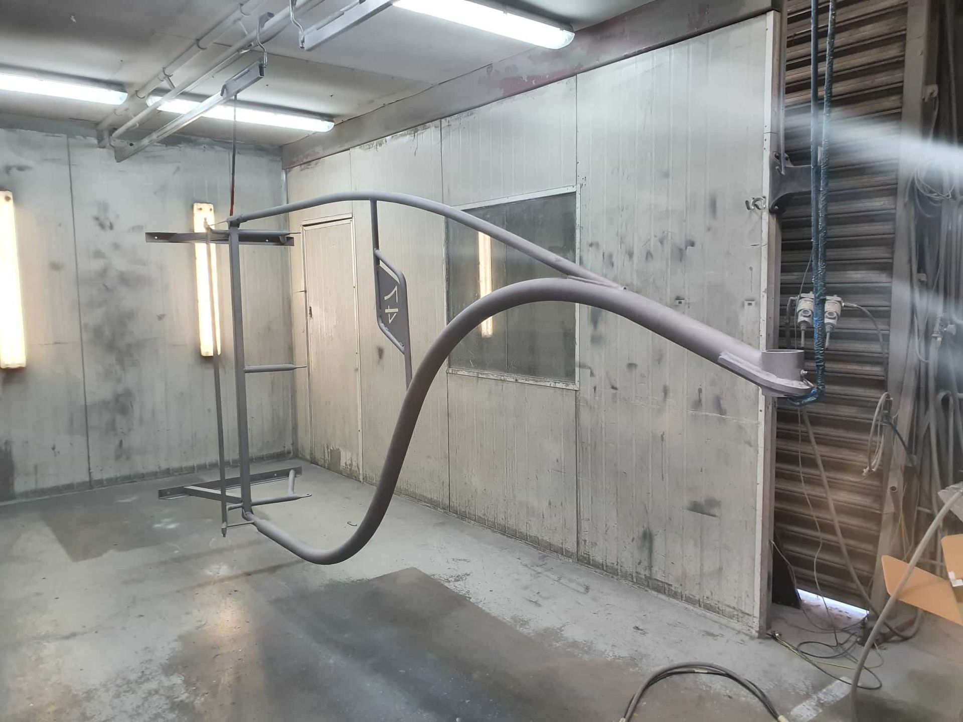 A Metal Pipe Is Being Spray Painted In A Room — Border Security Doors & Powder Coating in Wodonga, VIC