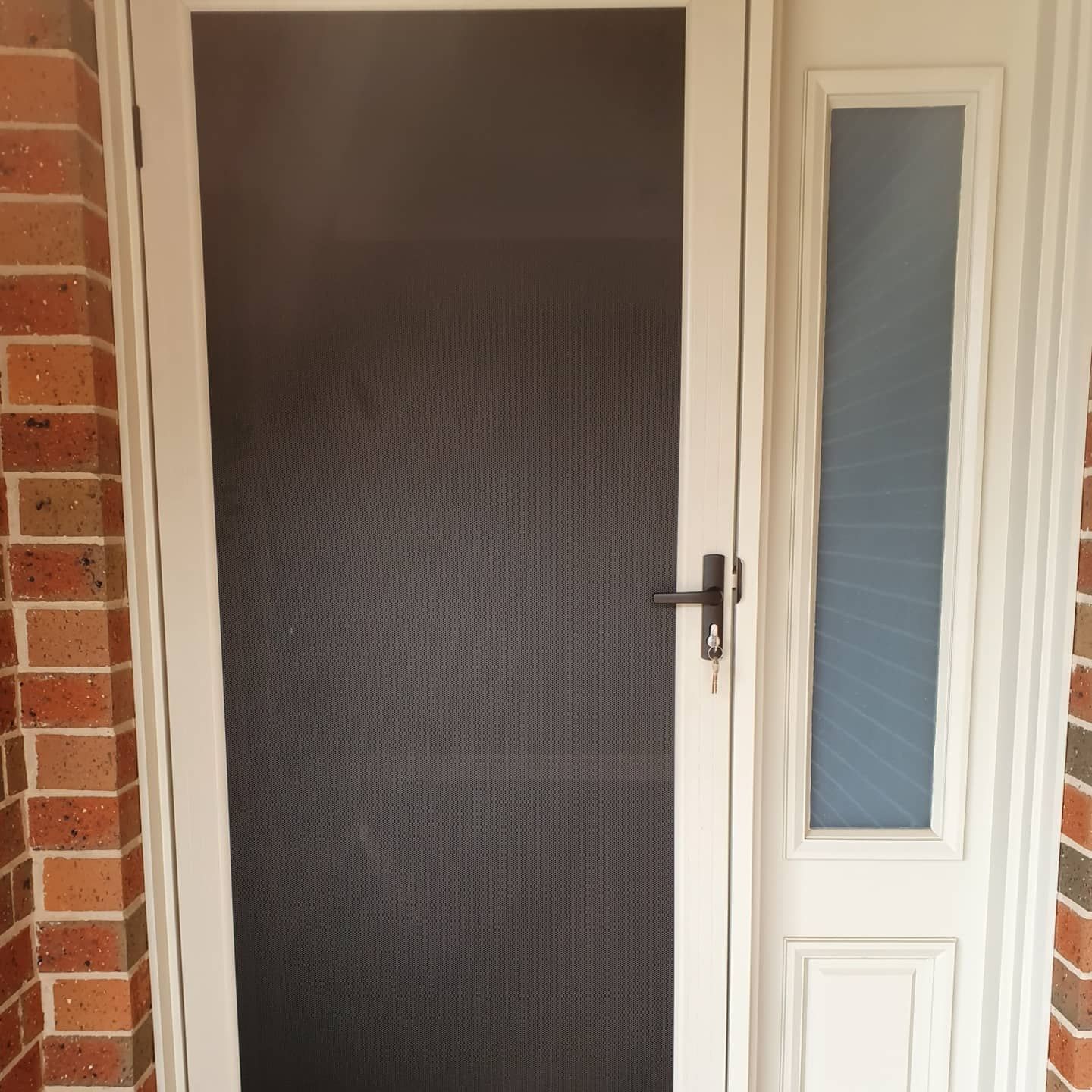 A White Door With A Screen And A Window On A Brick Wall — Border Security Doors & Powder Coating in Wodonga, VIC
