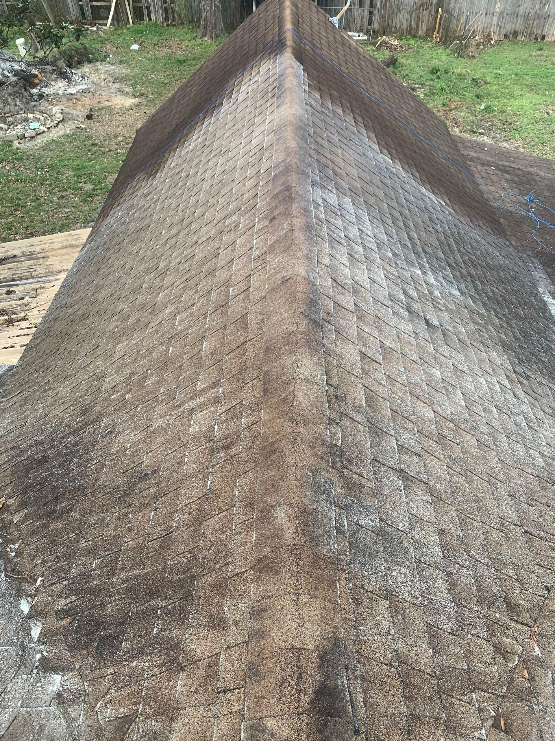A close-up of a weathered, textured, dark gray, and tan roof.