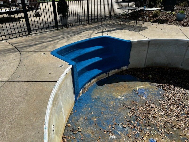 A blue staircase is painted on the side of a pool.
