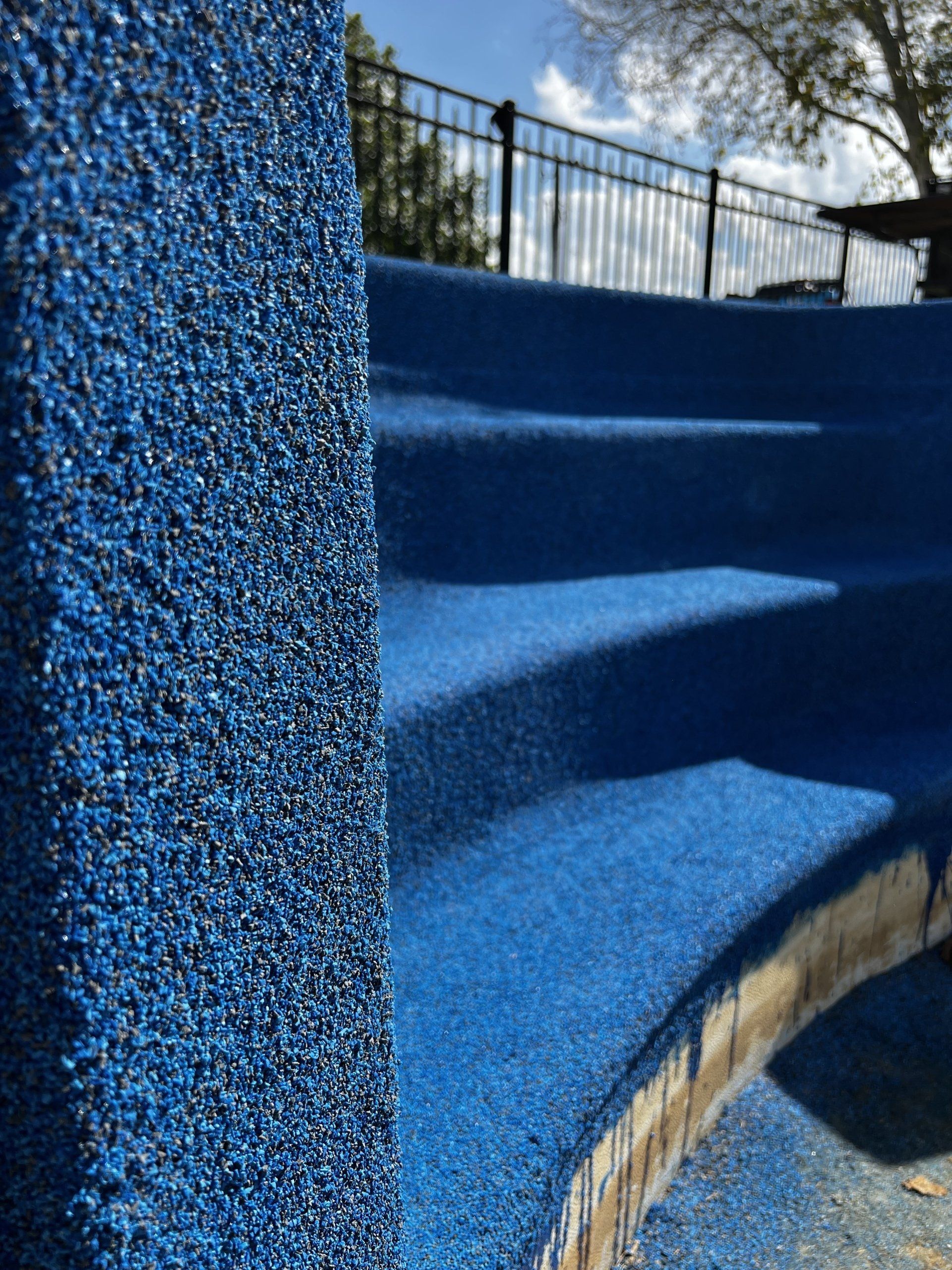 A close up of a blue staircase with a fence in the background.