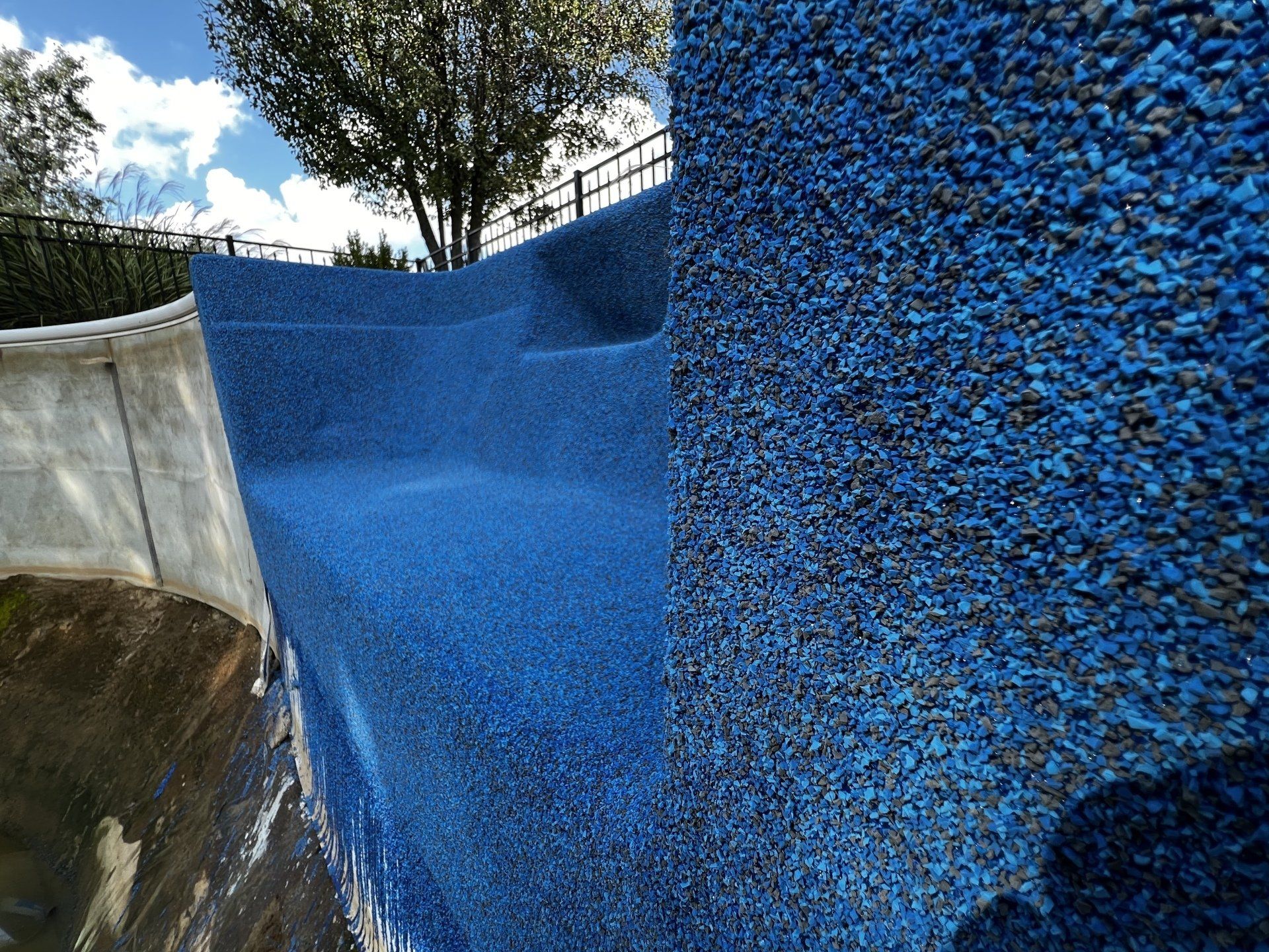 A close up of a blue wall with a tree in the background.