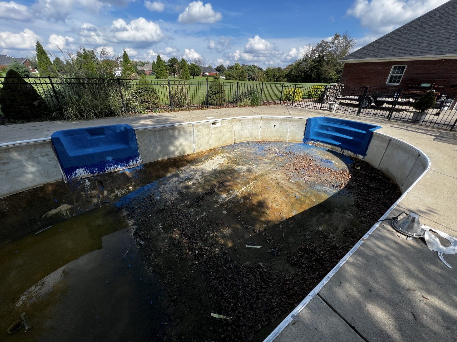 An empty swimming pool with a house in the background.