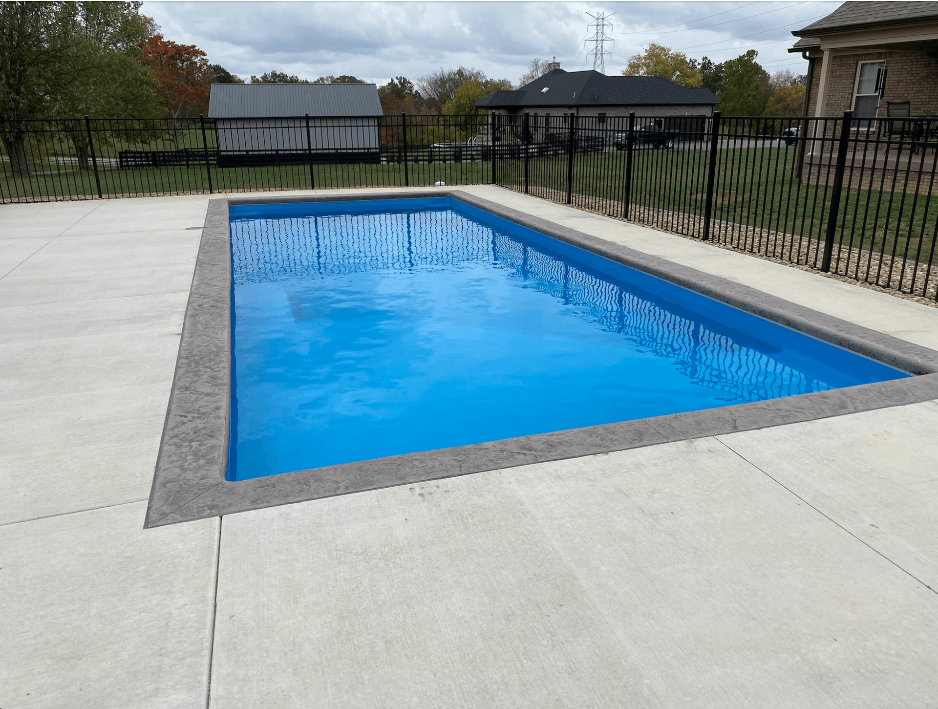 A large swimming pool with blue water is surrounded by a fence.