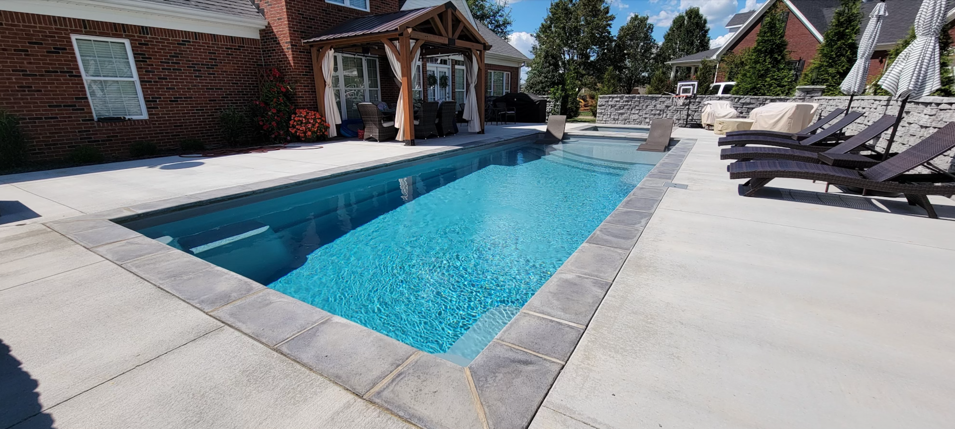 There is a large swimming pool in the backyard of a house.