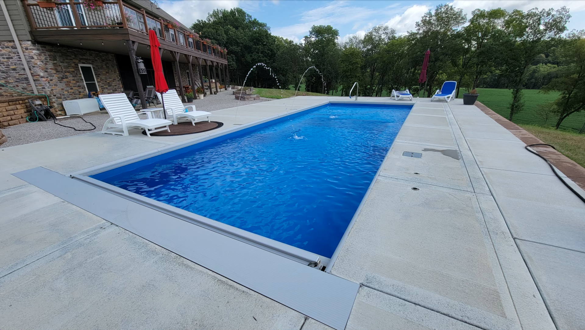 There is a large swimming pool in the backyard of a house.