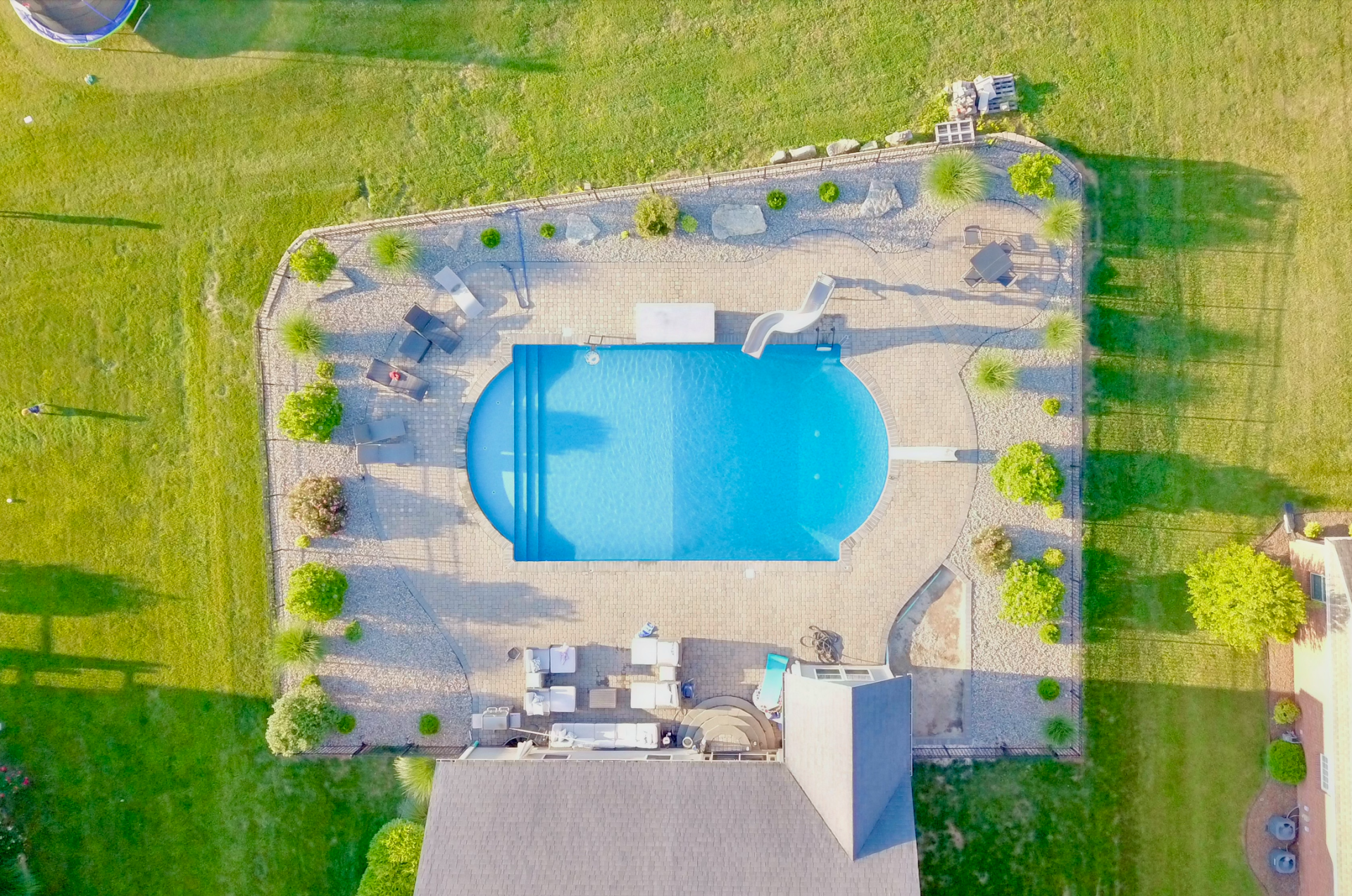 An aerial view of a large swimming pool in the backyard of a house.