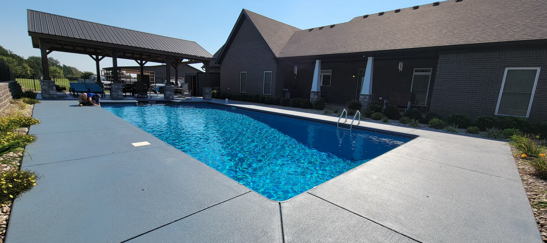 There is a large swimming pool in the backyard of a house.