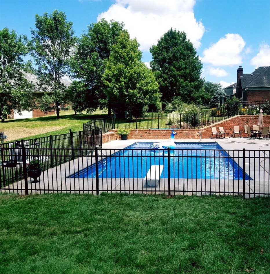 A large swimming pool is surrounded by a metal fence