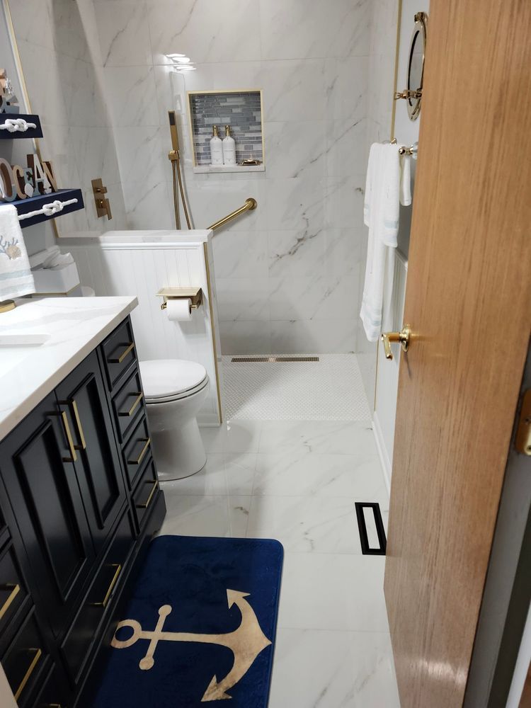 A bathroom with a toilet , sink , and rug with an anchor on it