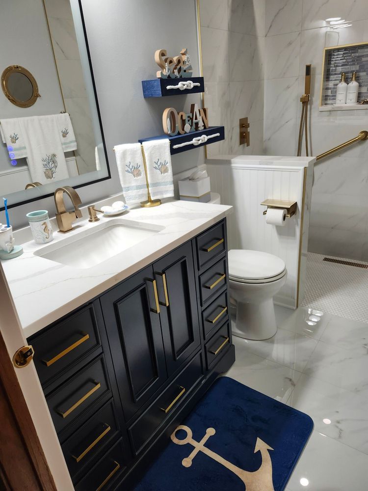 A bathroom with a sink , toilet , and anchor rug.