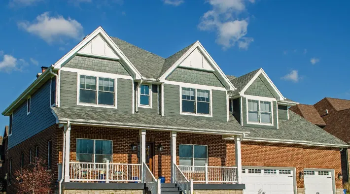 A large brick house with a green roof and white trim.