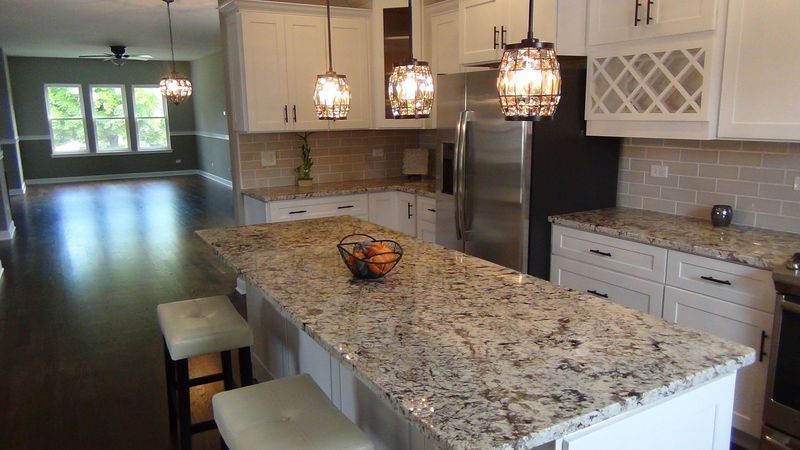 A kitchen with granite counter tops , white cabinets and stainless steel appliances.