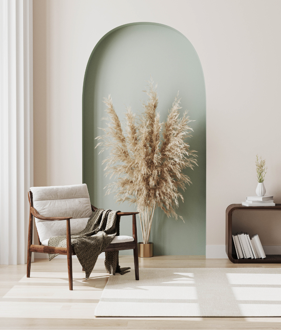 A living room with a chair and a plant in front of a green wall.