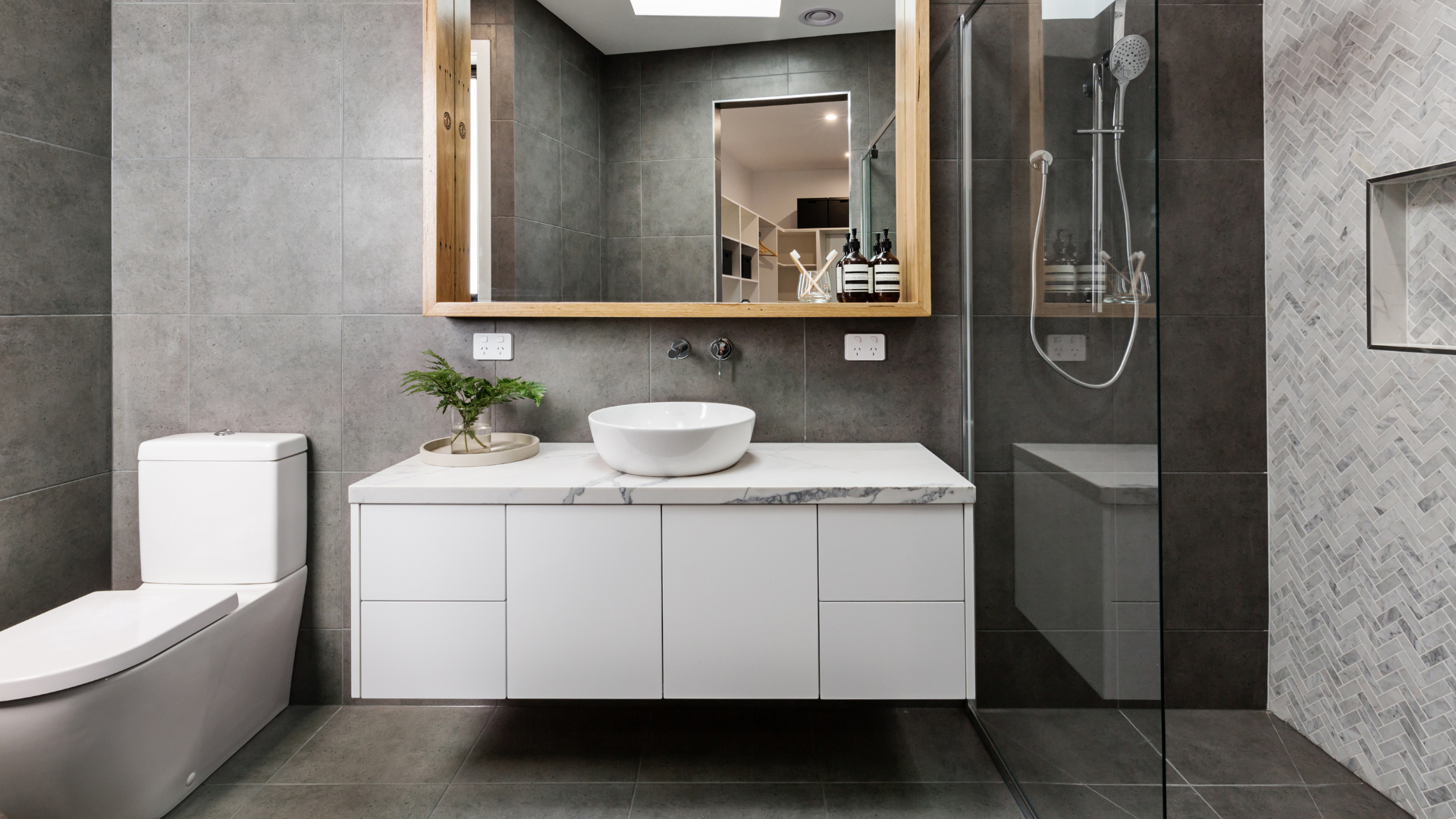 A bathroom with a toilet , sink , mirror and walk in shower.