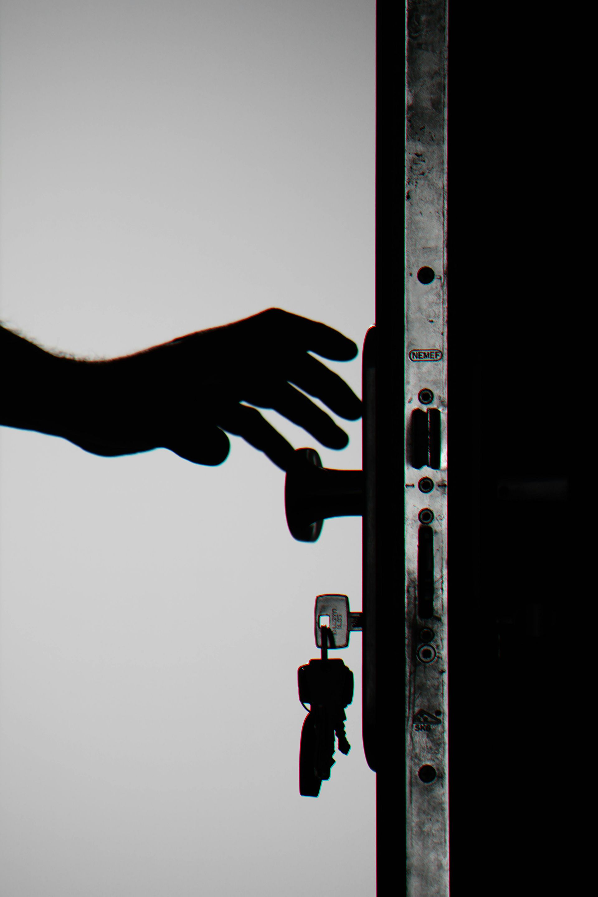 A silhouette of a hand opening a door with keys