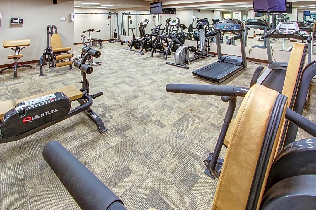 A large gym filled with lots of exercise equipment and a television.