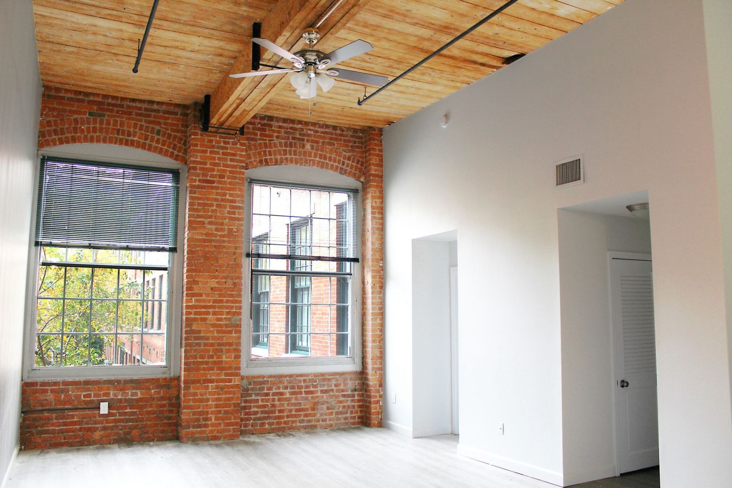 An empty room with brick walls and a ceiling fan