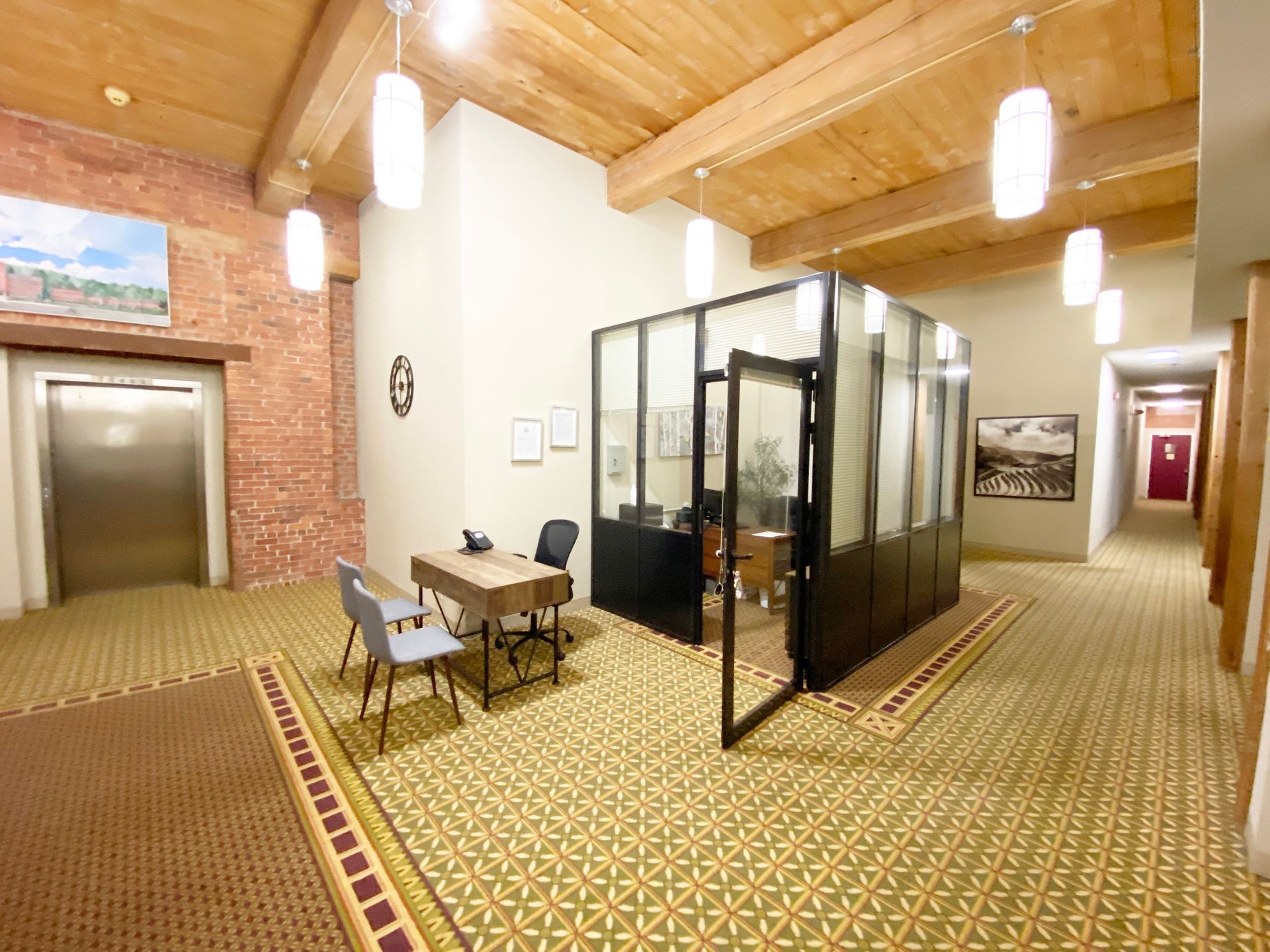 A hallway with a desk and chairs in the middle of it.