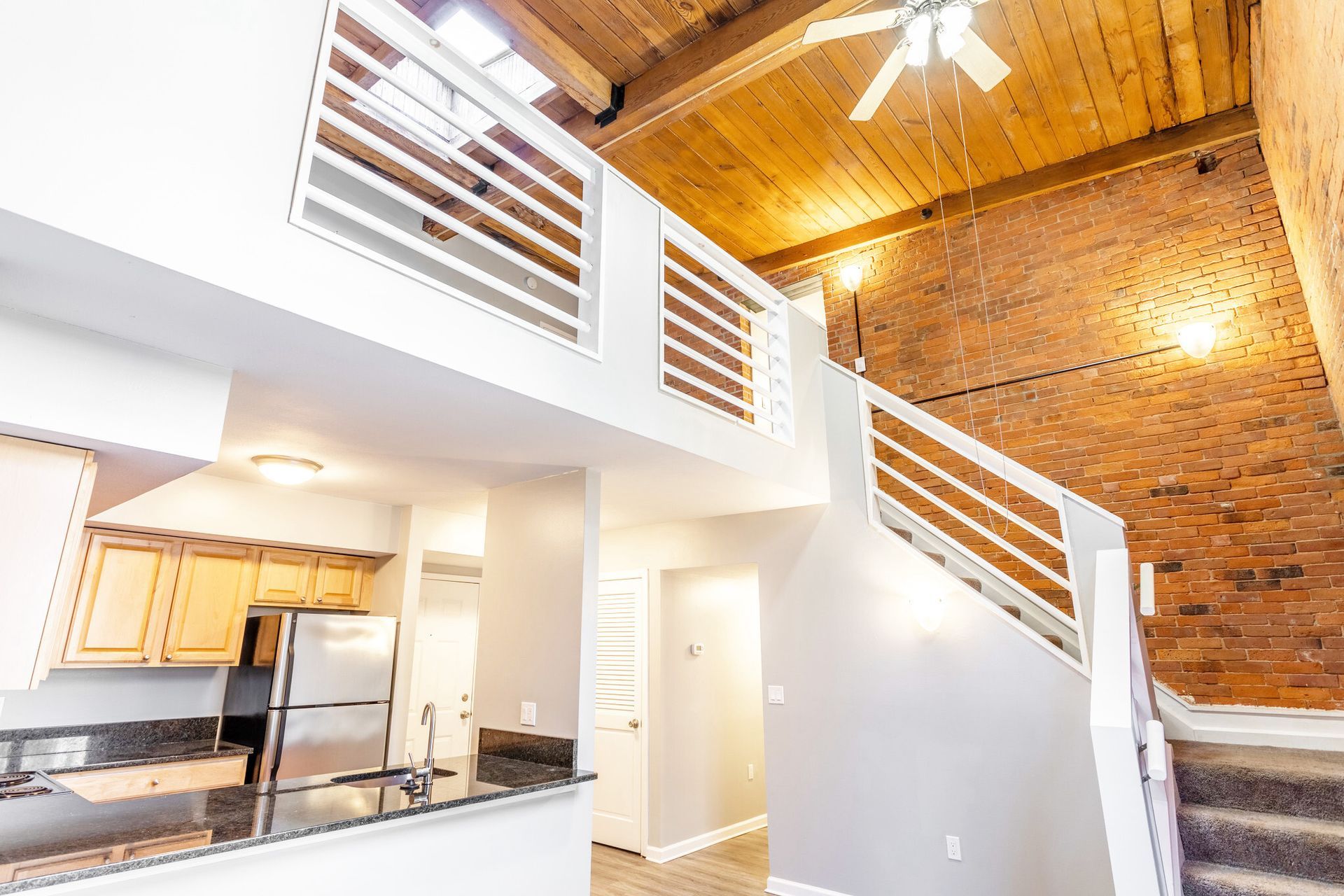 A kitchen with a staircase leading to the second floor and a ceiling fan.