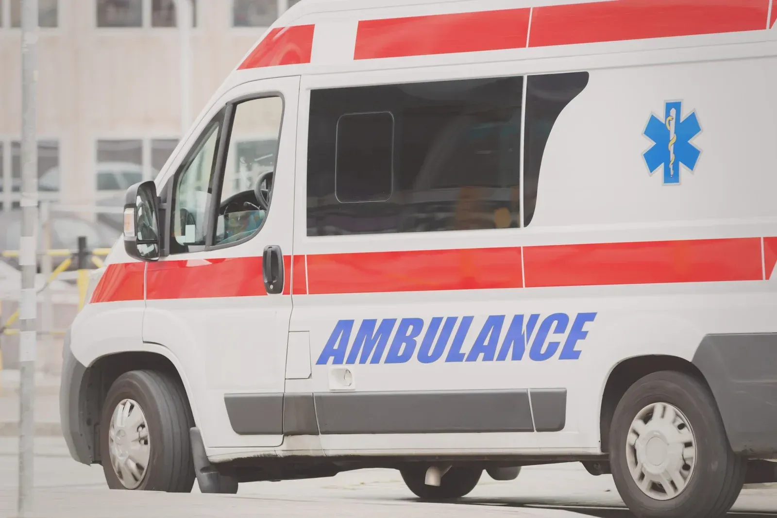 White ambulance with red stripes, blue medical symbol, and