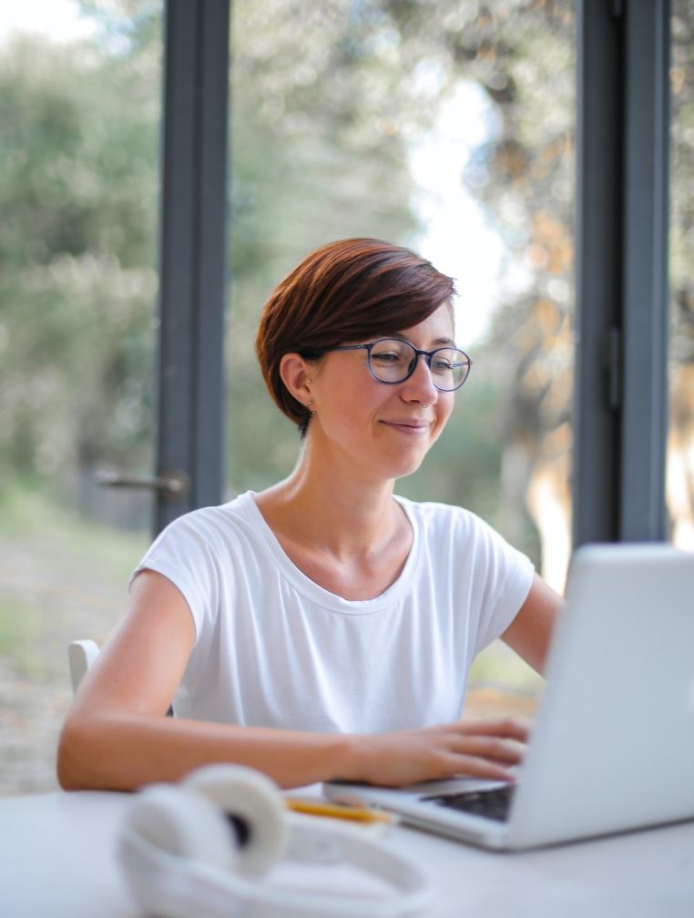 A woman is sitting at a table using a laptop computer.