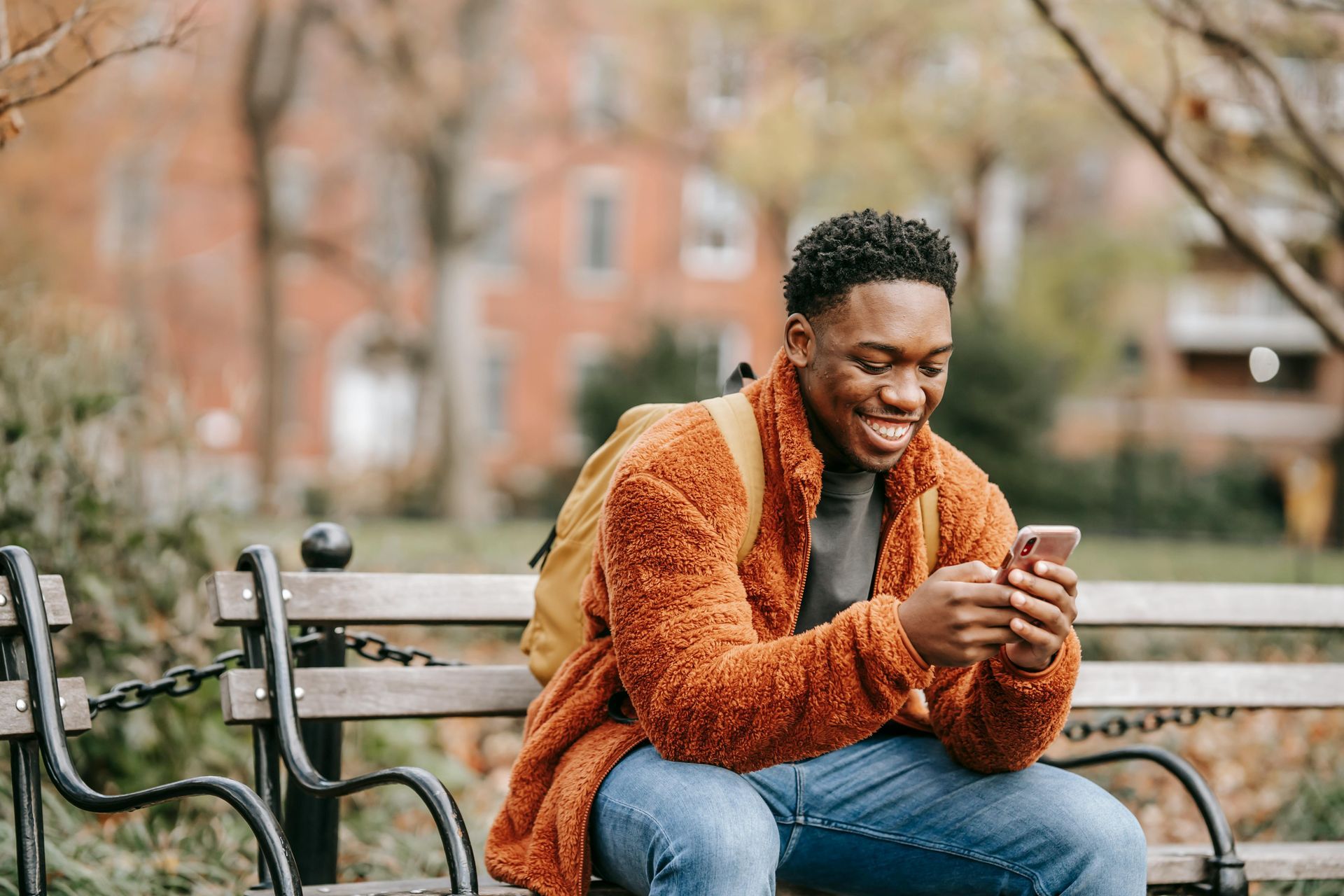 A man is sitting on a park bench looking at his cell phone.