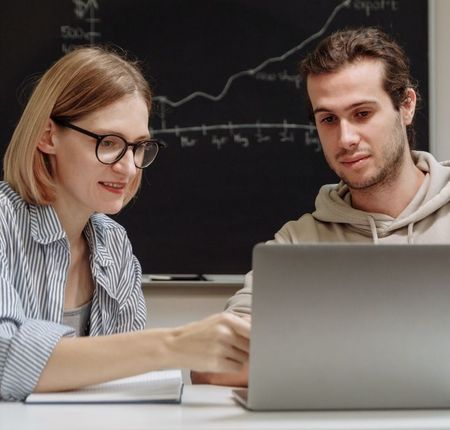 A man and a woman are looking at a laptop computer.