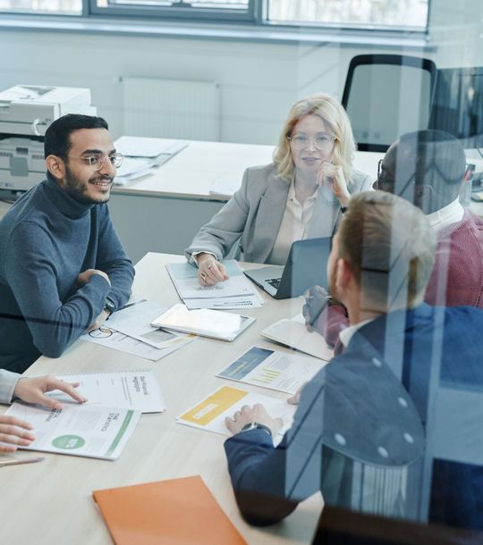 A group of people are sitting around a table having a meeting.